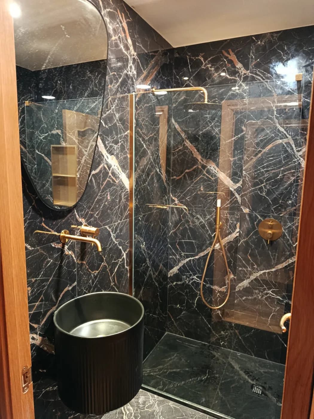 Baño de lujo efecto mármol negro con grifería dorada